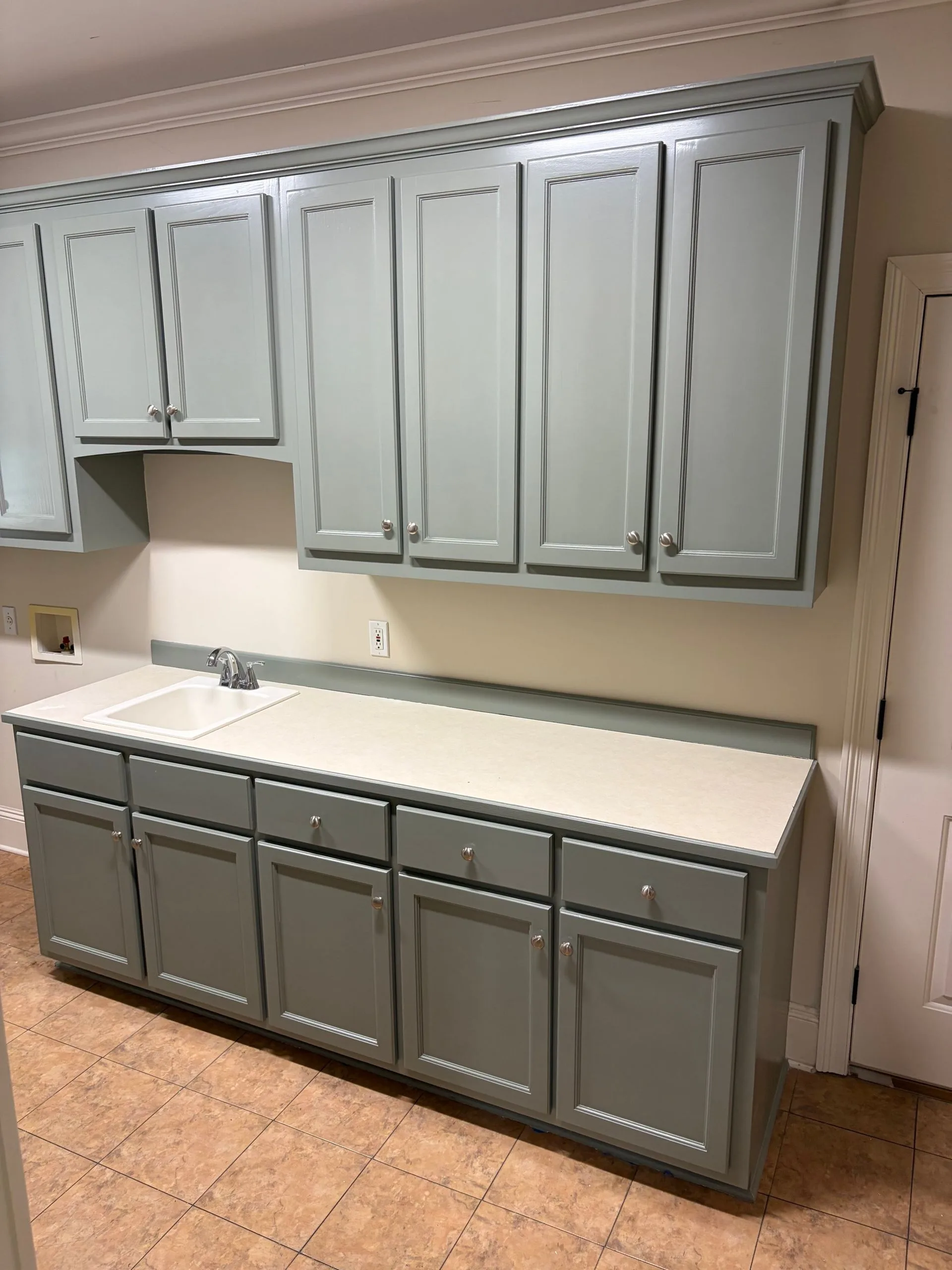Laundry room cabinets repainted sage green by 3H Construction