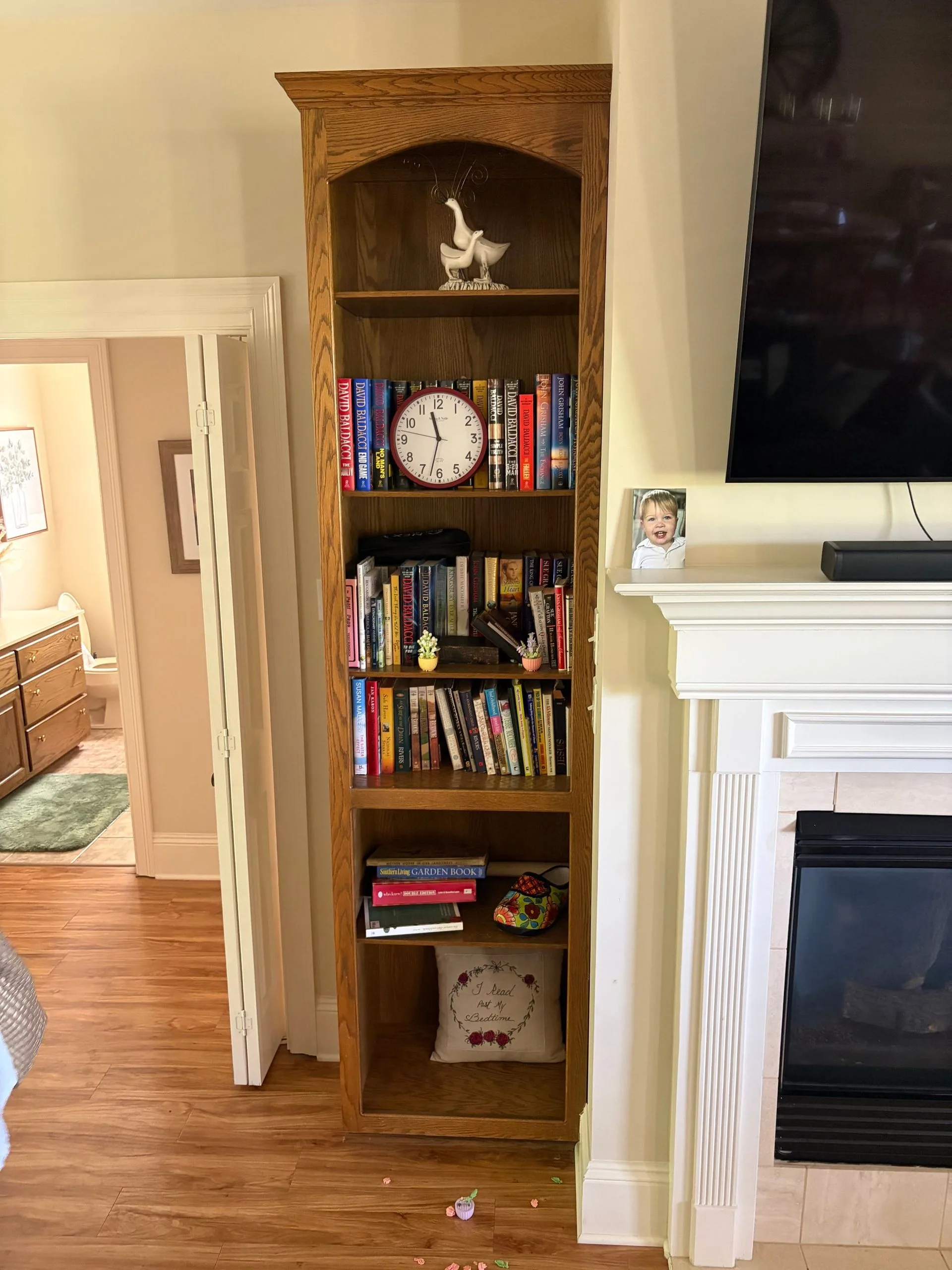 Natural oak bookcase beside a fireplace before repainting by 3H Construction