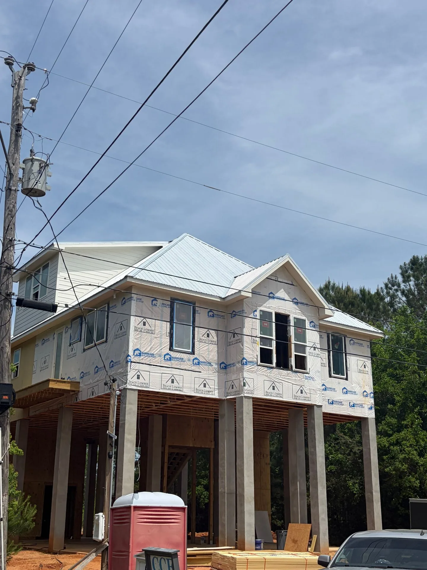 Elevated custom home with windows installed and metal roof being finished by 3H Construction