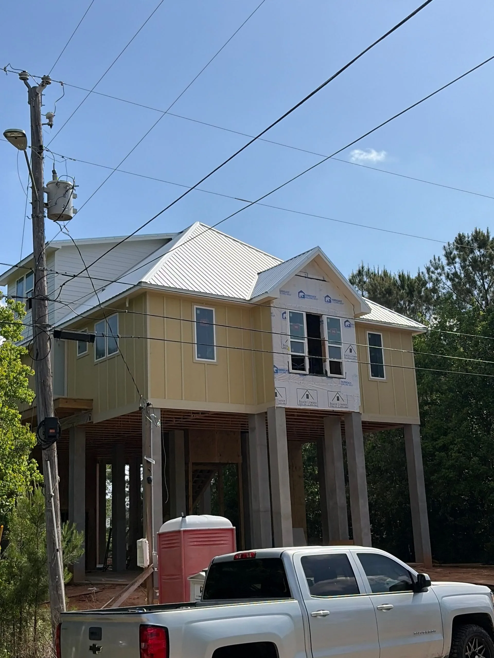Elevated home under construction on pilings with house wrap by 3H Construction