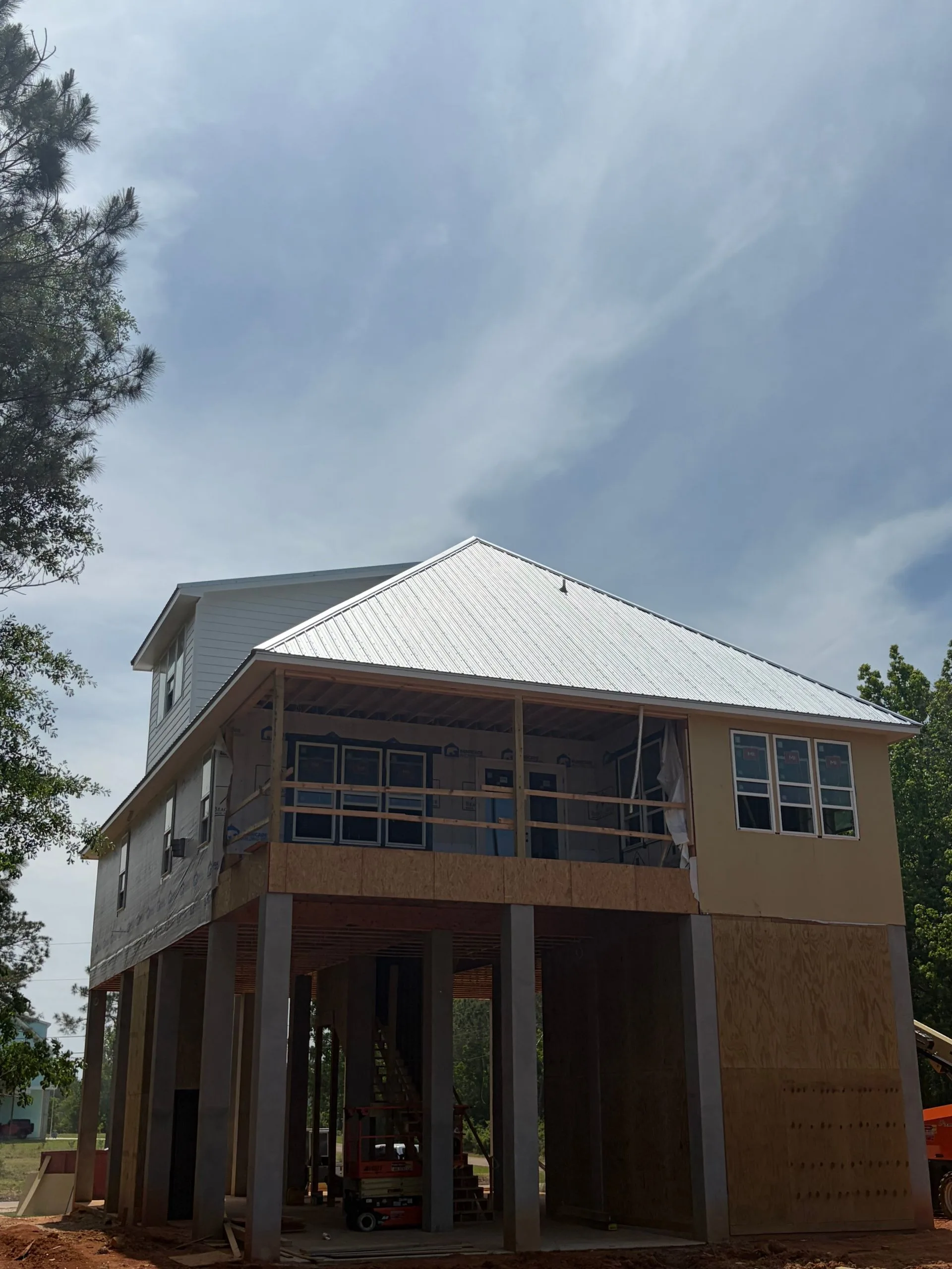 Elevated home with covered porch under construction by 3H Construction