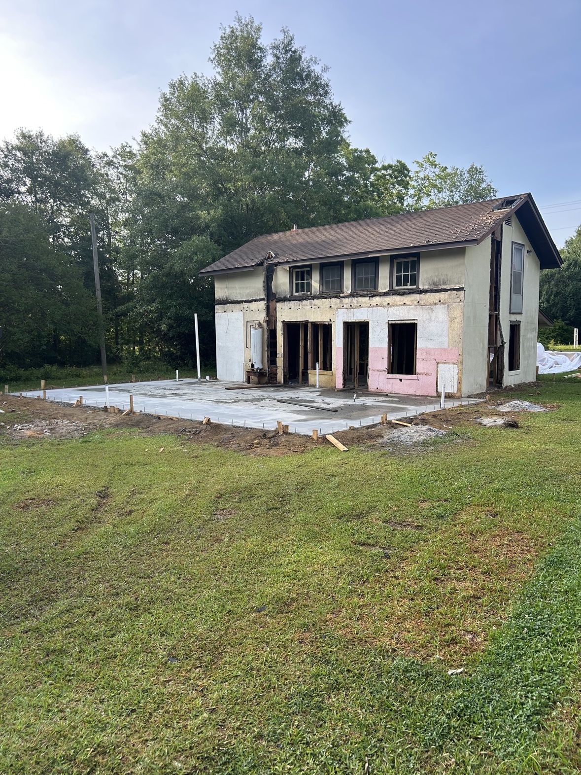Wide view of a new addition slab poured beside the original house