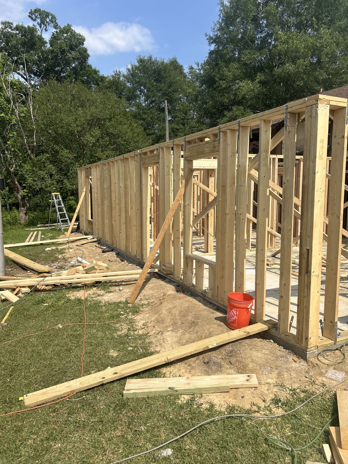 Home addition wall framing from a second angle, lumber and tools on site