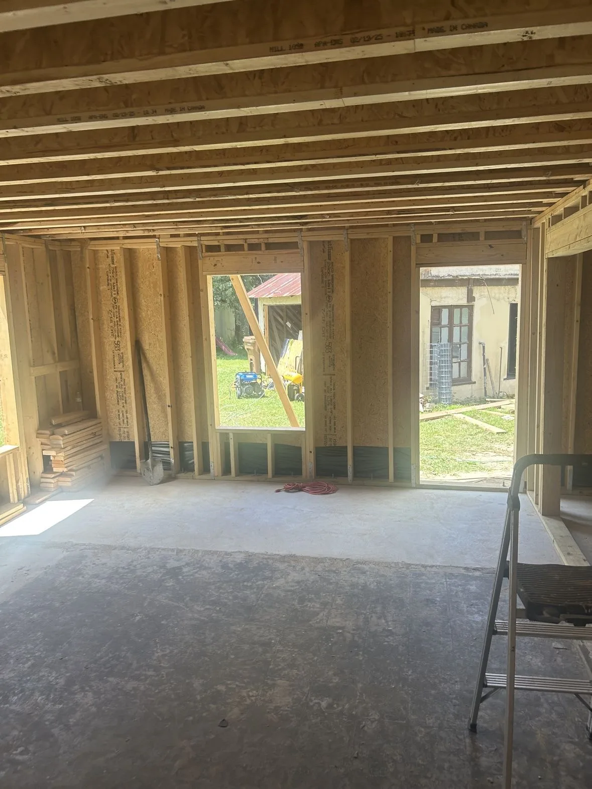 Interior view of a framed home addition looking back toward the original house