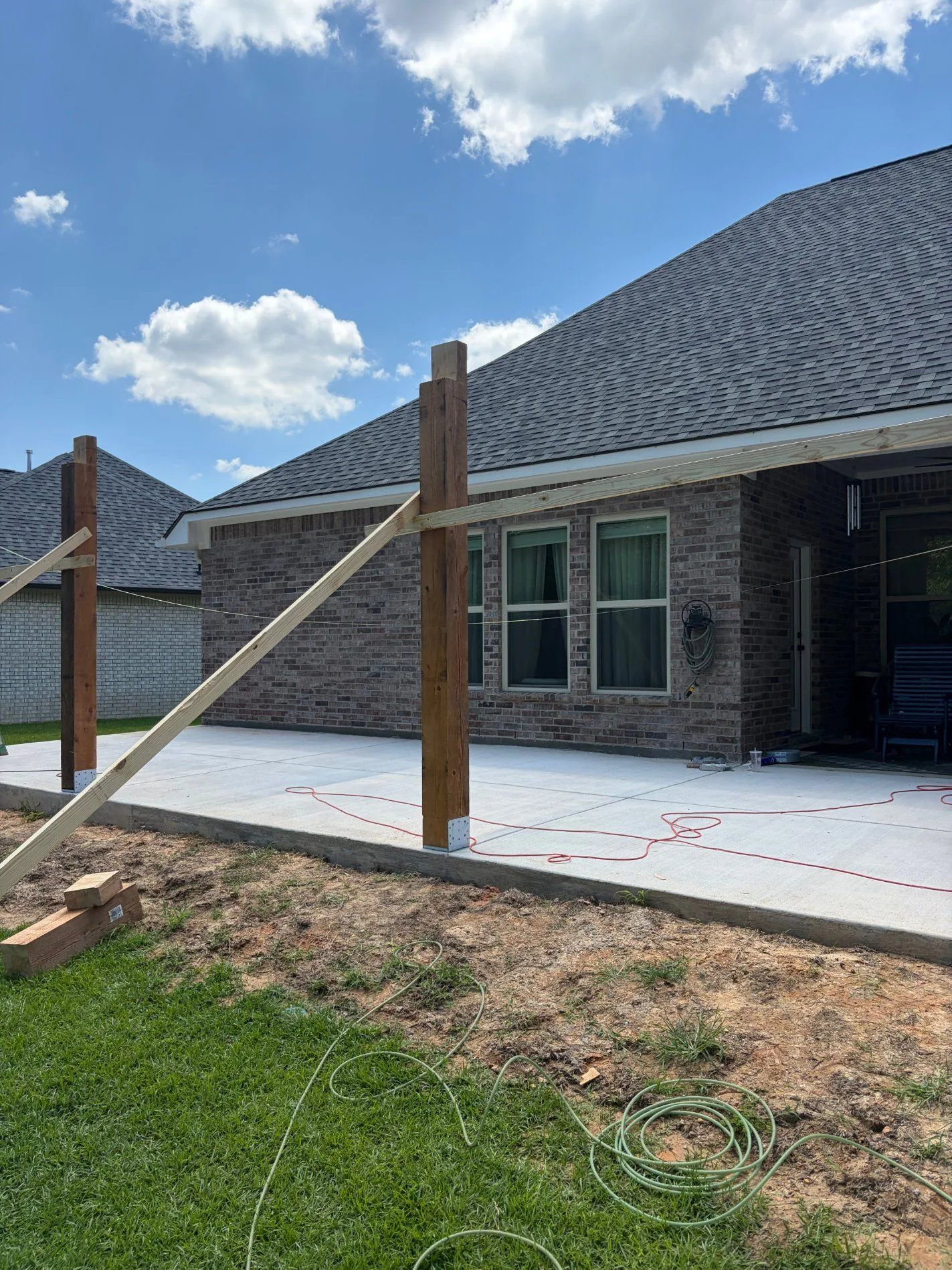 Cedar porch posts set on concrete patio with temporary bracing by 3H Construction