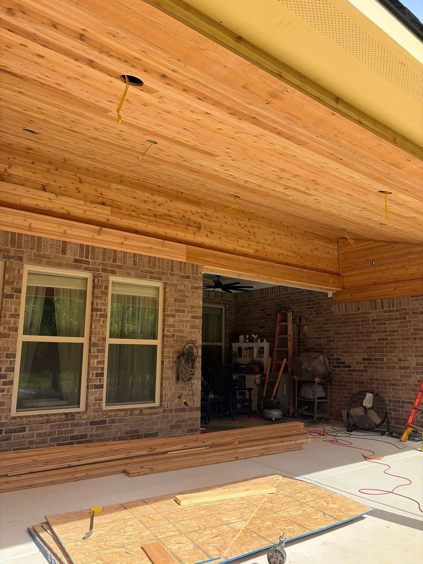 Nearly finished cedar porch ceiling with can-light wiring by 3H Construction