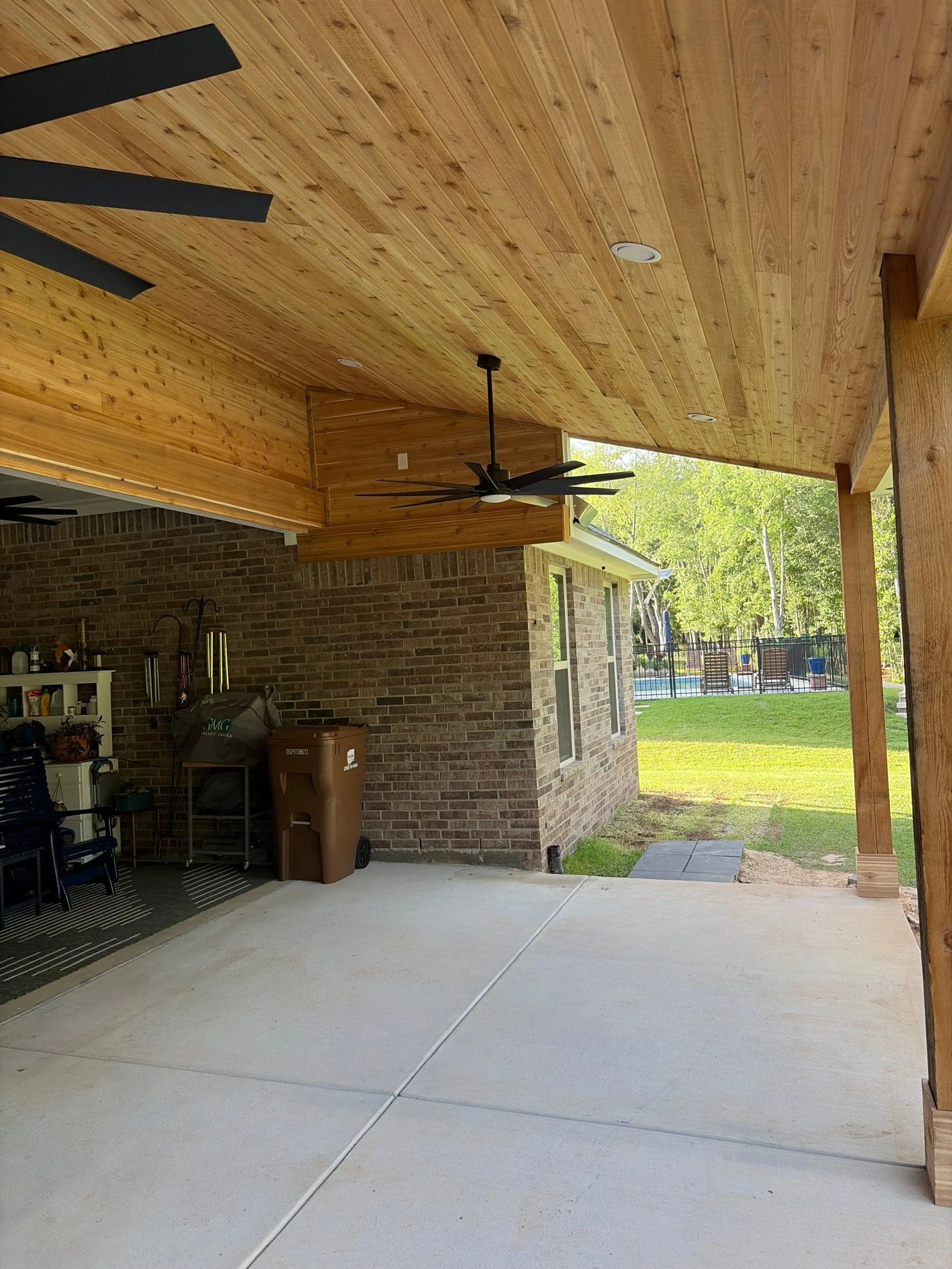 Covered patio with wood ceiling and ceiling fans by 3H Construction